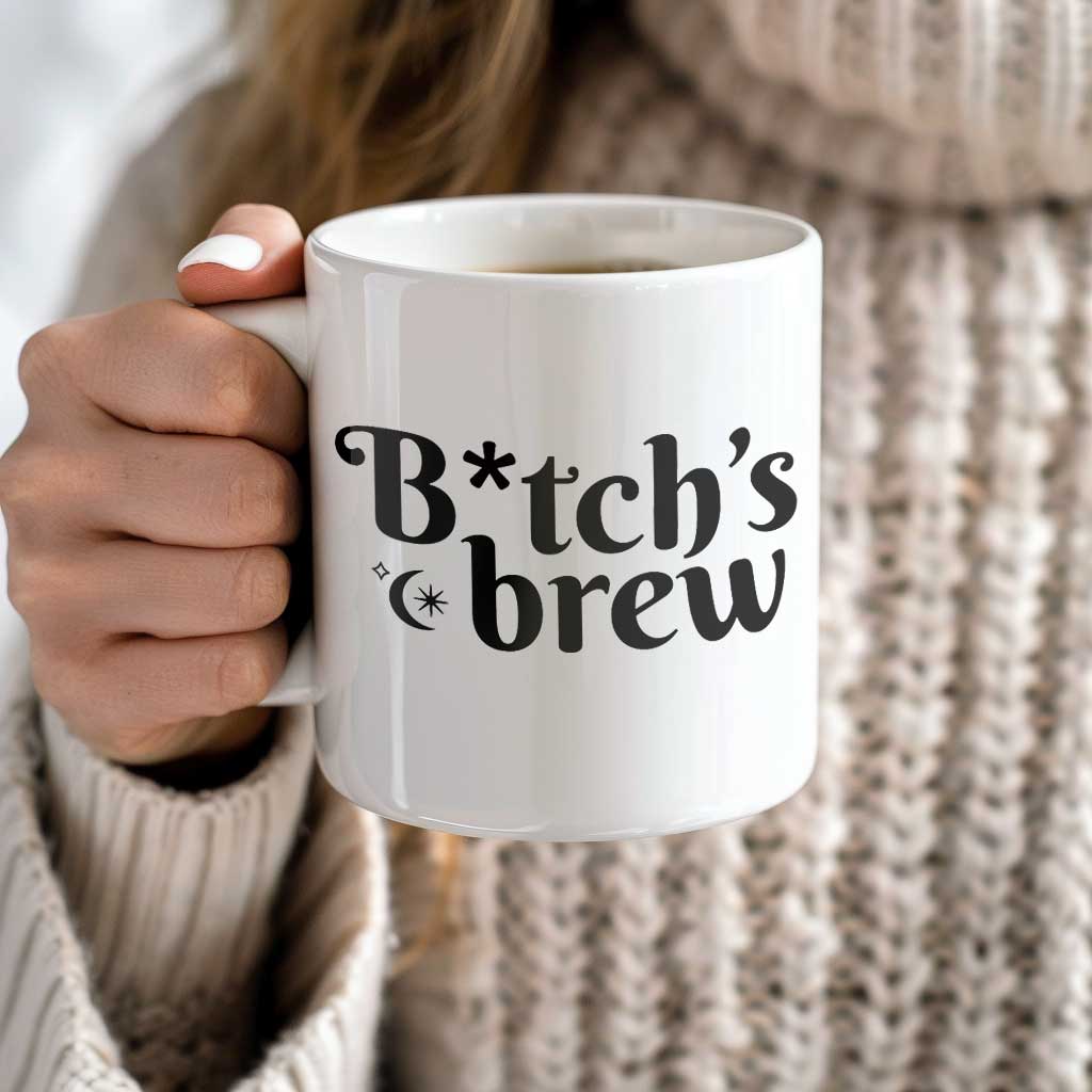 A woman holding a white ceramic coffee mug with the phrase B*tch's Brew on the side. 